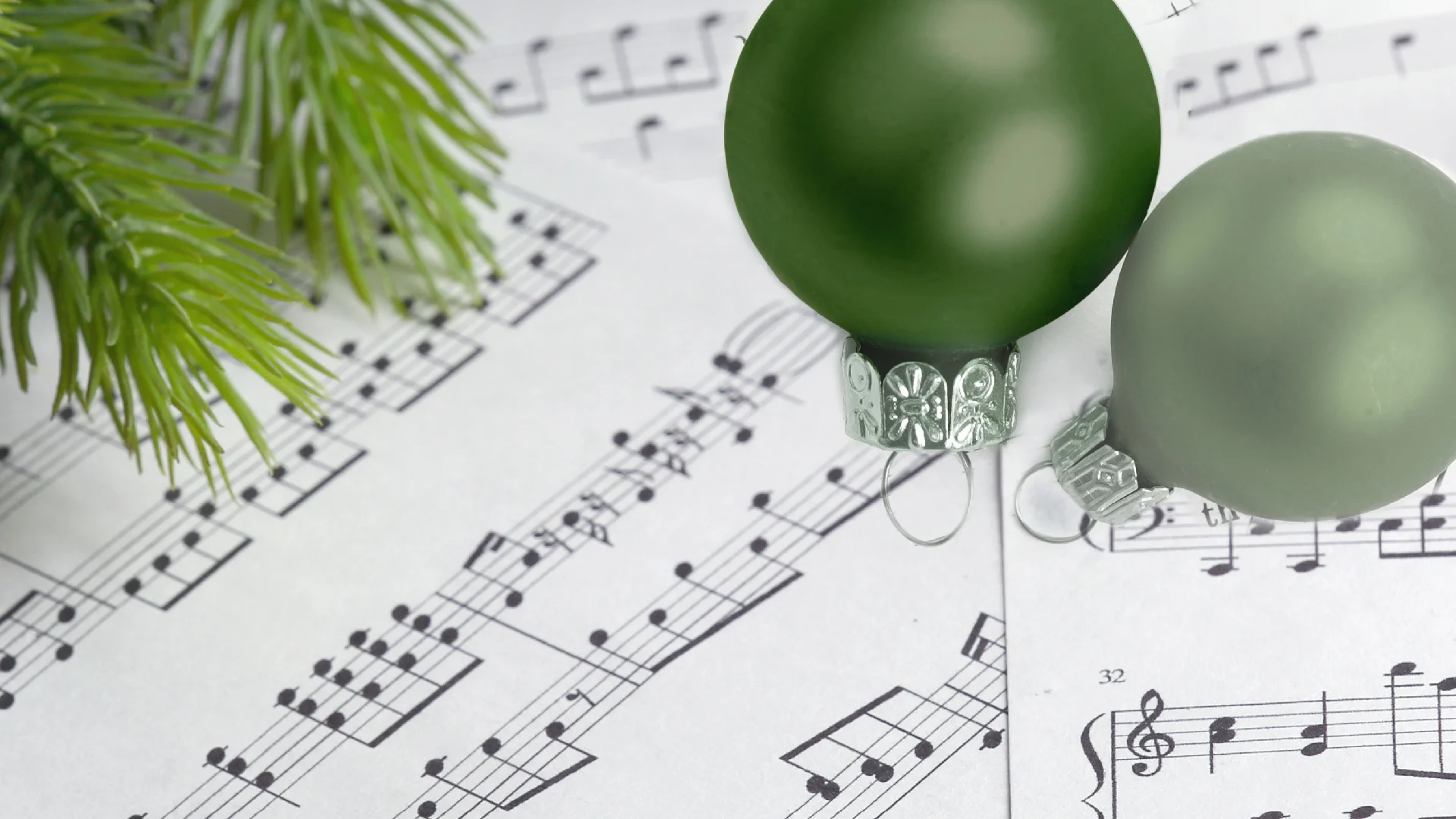 two green ornaments sitting on top of sheet music