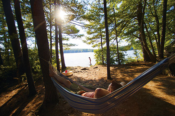 a person in a hammock at a campsite