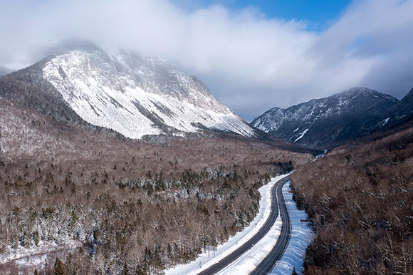 aerial view of a road cutting through mountains in the winter