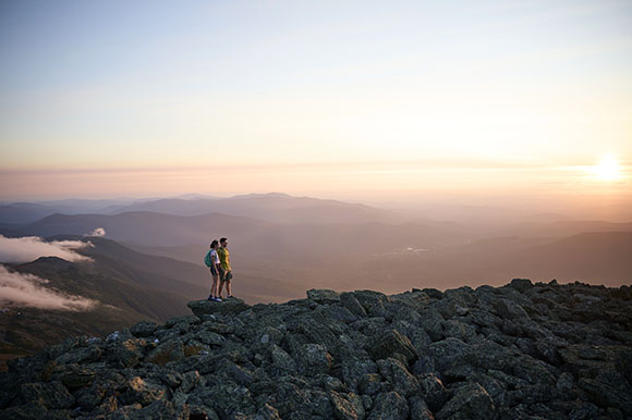 a man and woman standing on a mountain peak