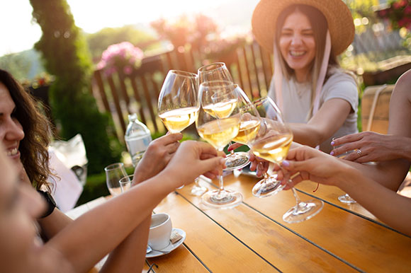 a group of people clincking glasses of white wine