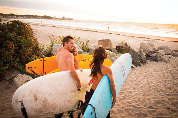 a group of 4 people carrying surfboards onto the beach
