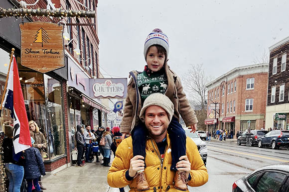 a man with a child on his shoulders on a main street in winter