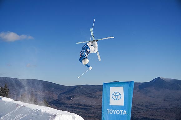 a skier doing a flip with mountains in the background