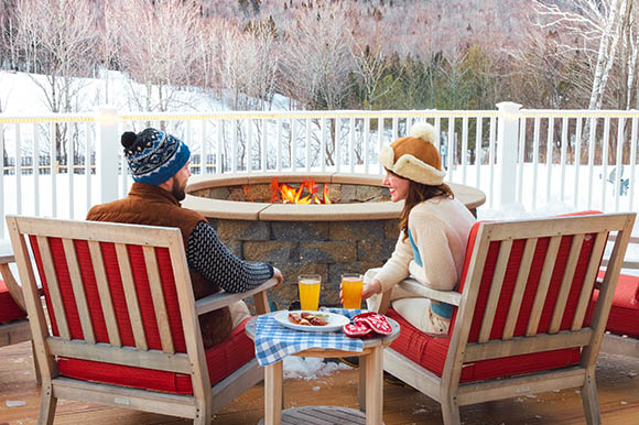 a man and woman sitting outside by a fire pit