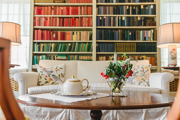 a tea pot on a table wtih bookshelves behind it