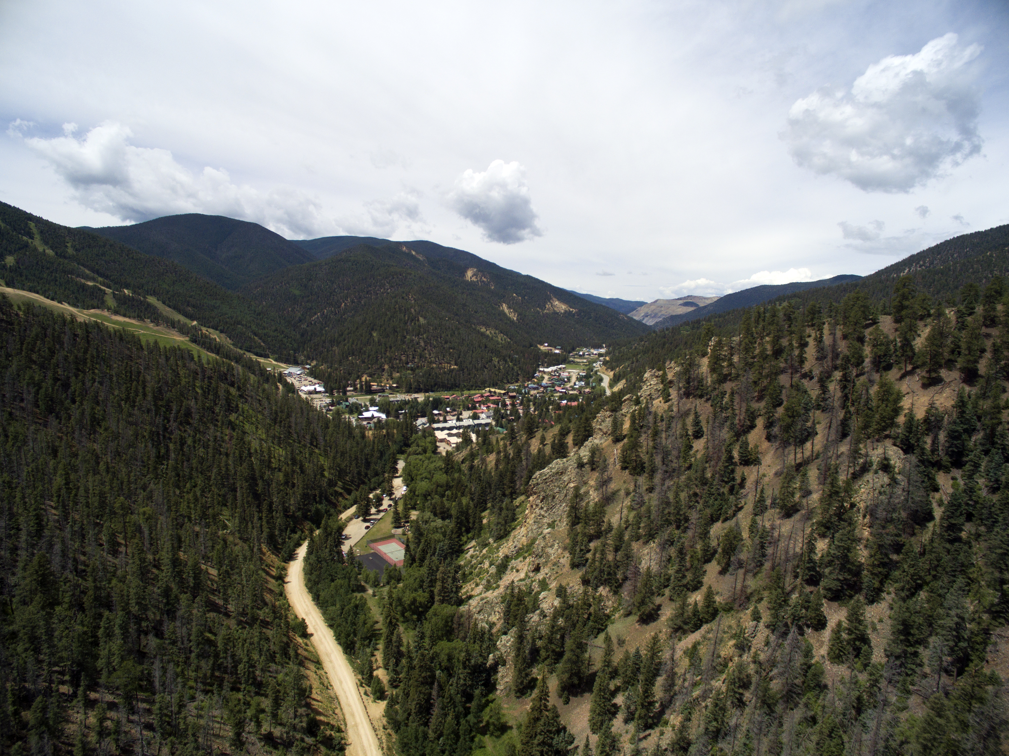rolling mountainsides with green trees surrounding a small town in a valley