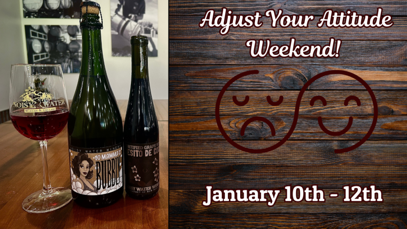 Promotional image featuring two bottles of wine, one from Noisy Water Winery and another from Stio DeMama, next to a wine glass half-filled with red wine. In the background, a wooden panel with a whimsical design of two smiling theater masks and text announcing 'Adjust Your Attitude Weekend!' from January 10th to 12th.