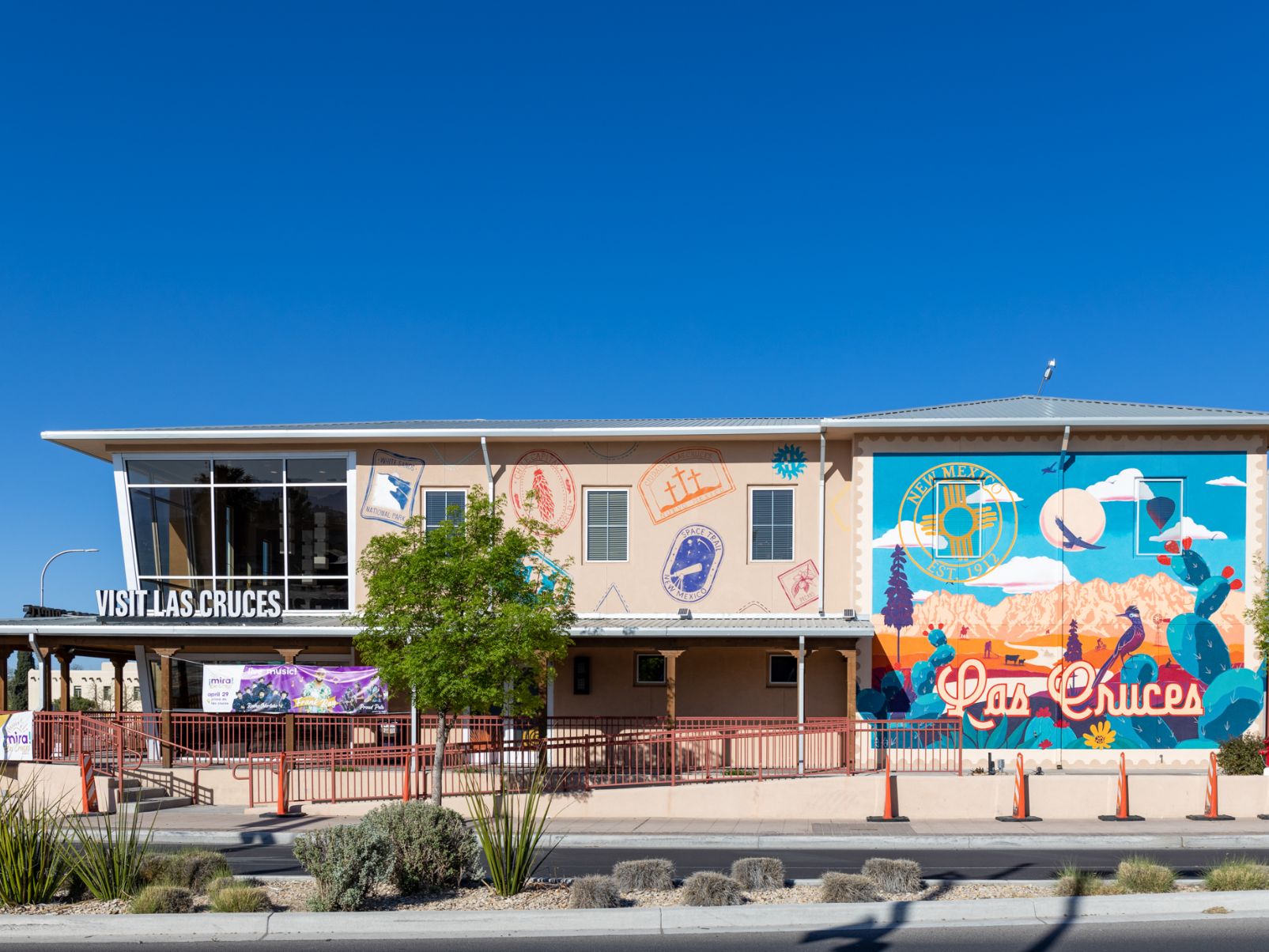 Exterior view of the Visit Las Cruces building, adorned with colorful murals showcasing local culture and attractions, under a clear blue sky.