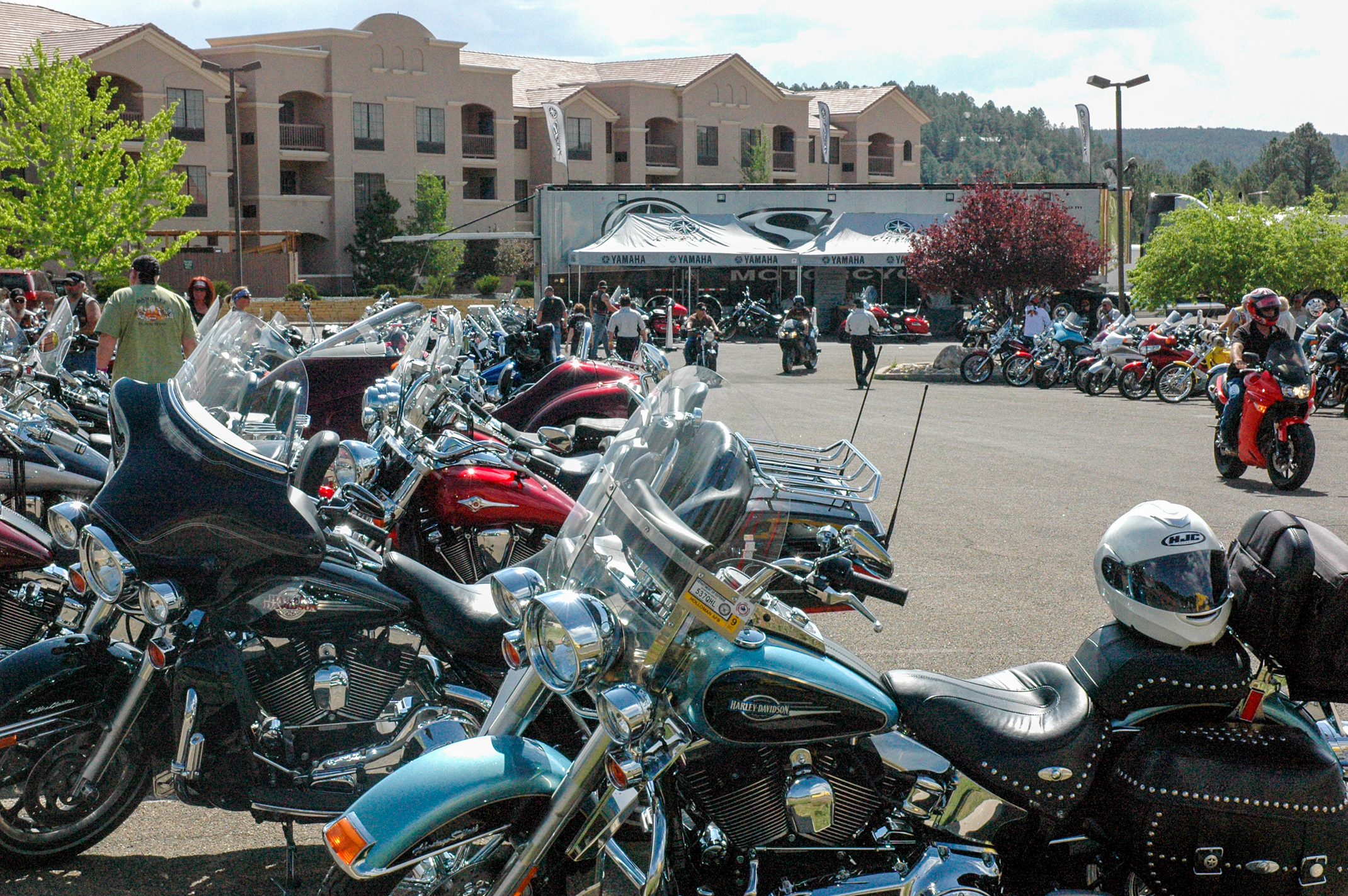 A parking lot filled with various motorcycles in front of vendor tents on a sunny day.