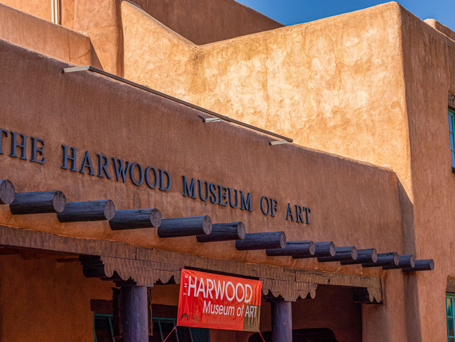 Exterior view of The Harwood Museum of Art, featuring its beige adobe architecture and signage.