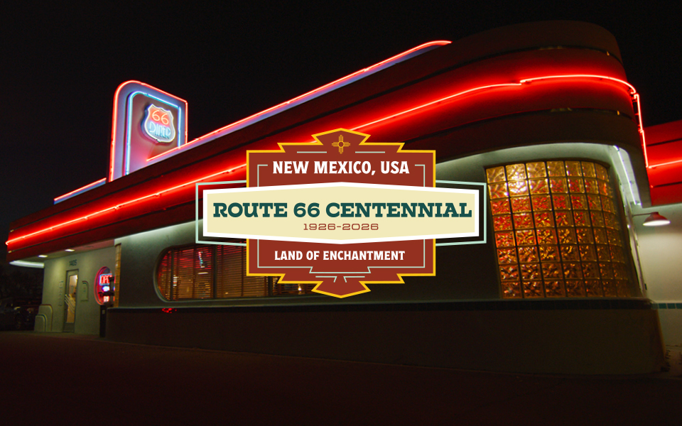 Illuminated Route 66 diner in New Mexico, USA, celebrating the Route 66 Centennial with neon lights and a banner that reads "1928-2028 Land of Enchantment.