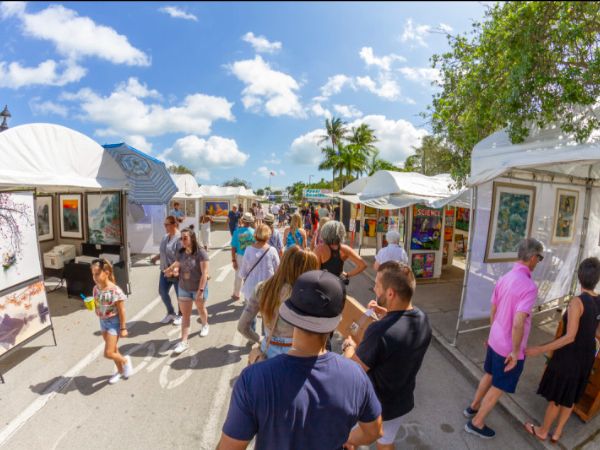 Outdoor art festival with visitors browsing various booths under a clear sky.