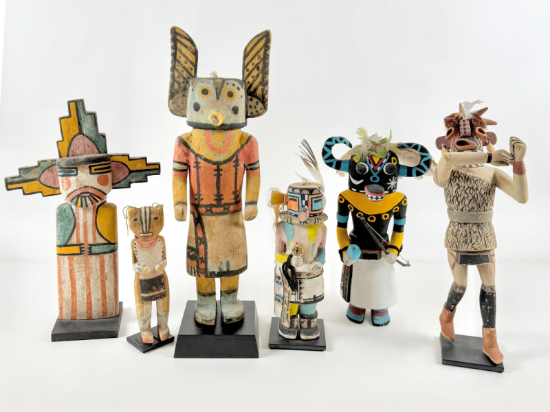 A collection of Indigenous kachina dolls, each uniquely decorated and representing different spiritual figures, displayed against a white background.