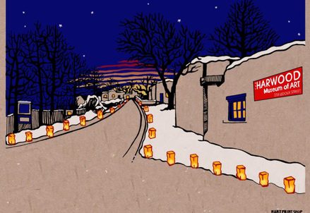Evening view of a snowy street lined with luminarias leading to the Harwood Museum of Art, under a starry sky with twilight hues.