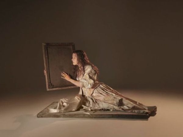  Generate by AI Assist  Person in an elegant dress crouches on the ground holding a mirror in front of a blank background.