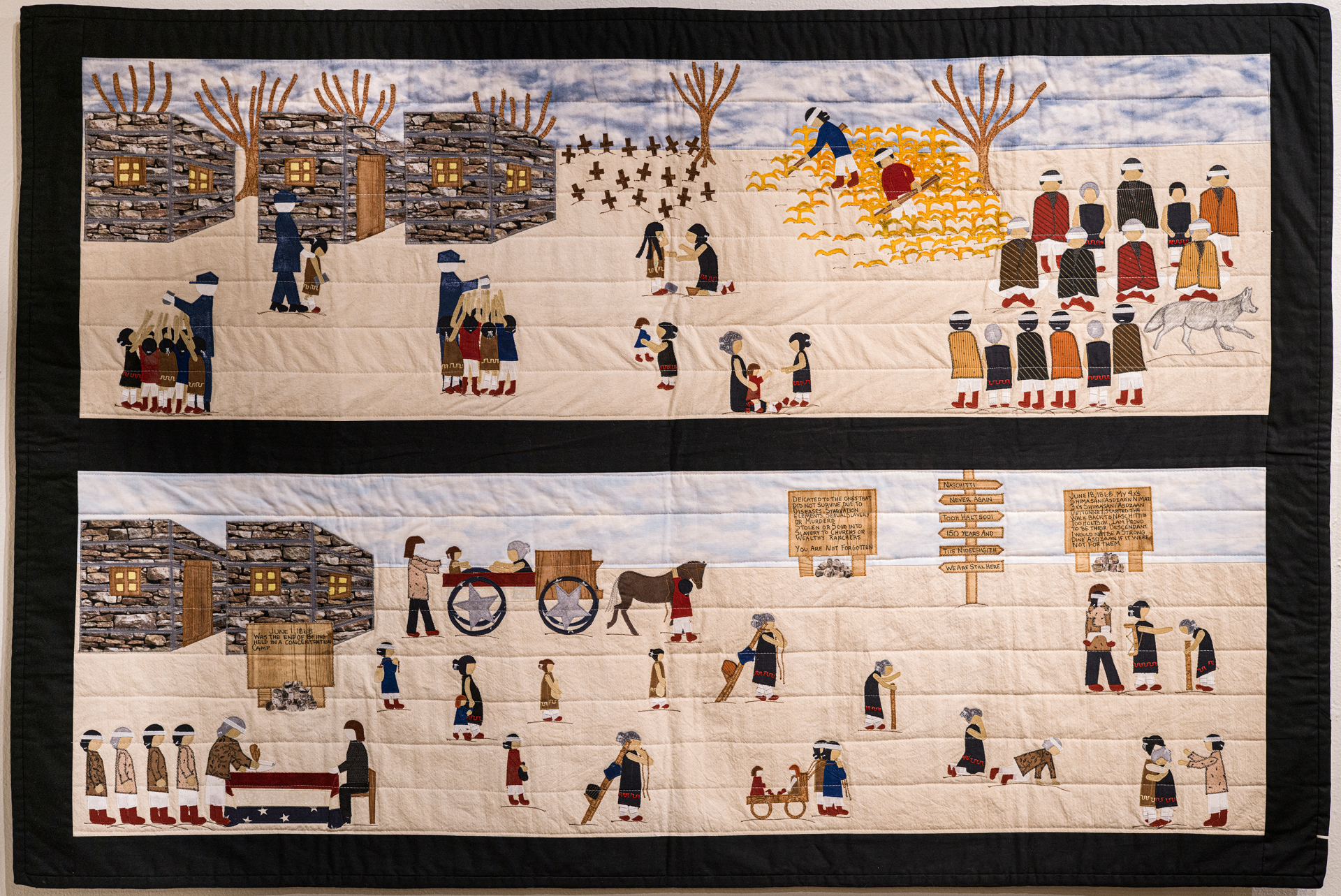 Quilt depicting various scenes of life on a Native American reservation, featuring interactions among people, buildings, and nature.