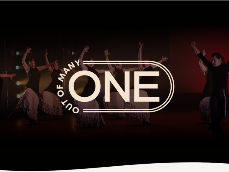 A group of performers in black and white attire dance energetically on stage, with arms raised. The backdrop transitions from a dark to reddish hue. Overlaid in the center is the phrase "Out of Many, One" in bold text.