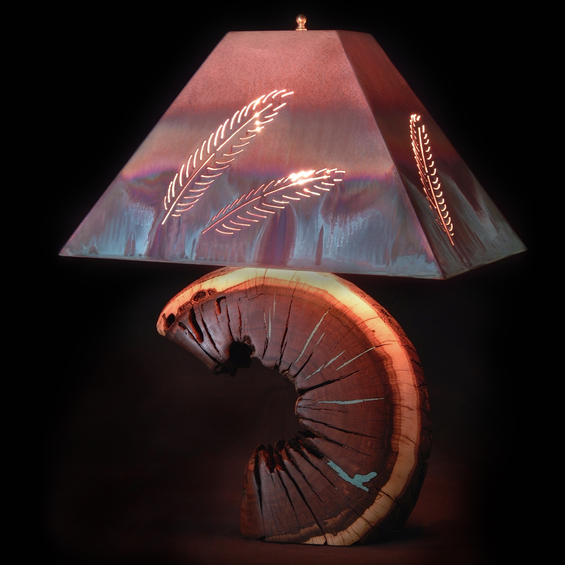 A uniquely designed lamp with a rustic wooden base that resembles a crescent moon, featuring a smooth polished texture. The lamp's shade is metallic and angular, adorned with intricate feather patterns that emit light. The background is dark, emphasizing the lamp's artistic details.