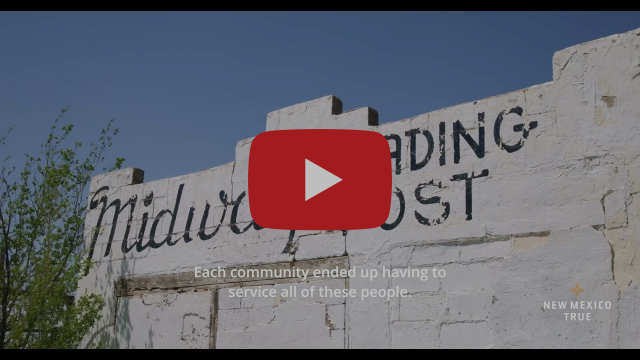 A weathered building exterior sits in front of a clear sky, the exterior reads Midway Trading Post