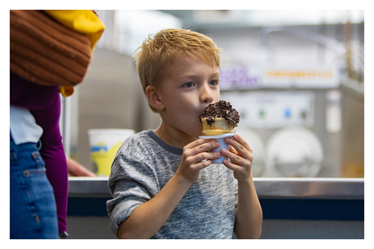 Young boy enjoys a chocolate-covered ice cream cone at a Niagara Falls ice cream shop during a summer outing.