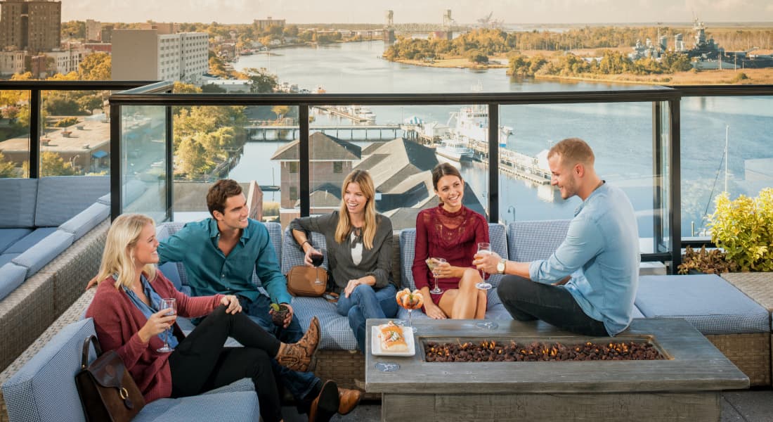 Friends seated together on a rooftop patio, taking in the stunning view of the water.