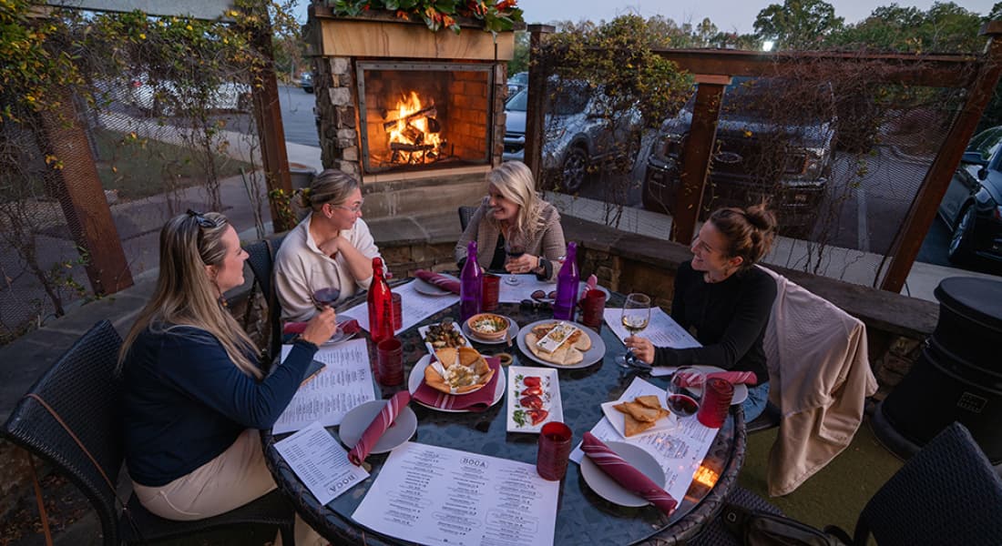 Several women gathered around an outdoor table at the Boca Restaurant in Hickory. Sharing laughter and food in a warm, inviting atmosphere.