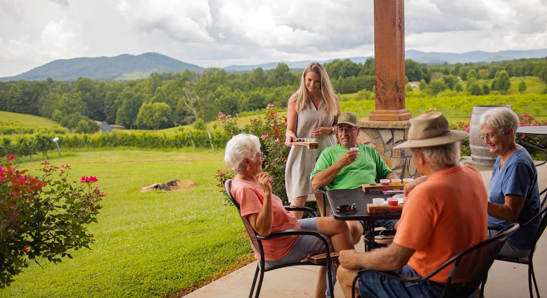 Group enjoying a wine tasting on the outdoor patio at Round Peak Vineyards in Mount Airy