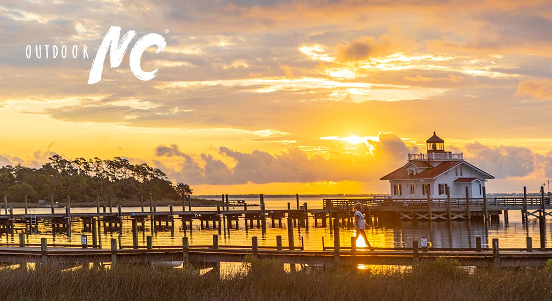 OUTDOOR NC - A serene sunset casts warm colors over a pier on the water.