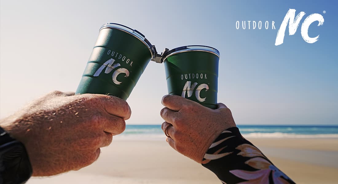 OUTDOOR NC - closeup showing toasting Outdoor NC cups on the beach