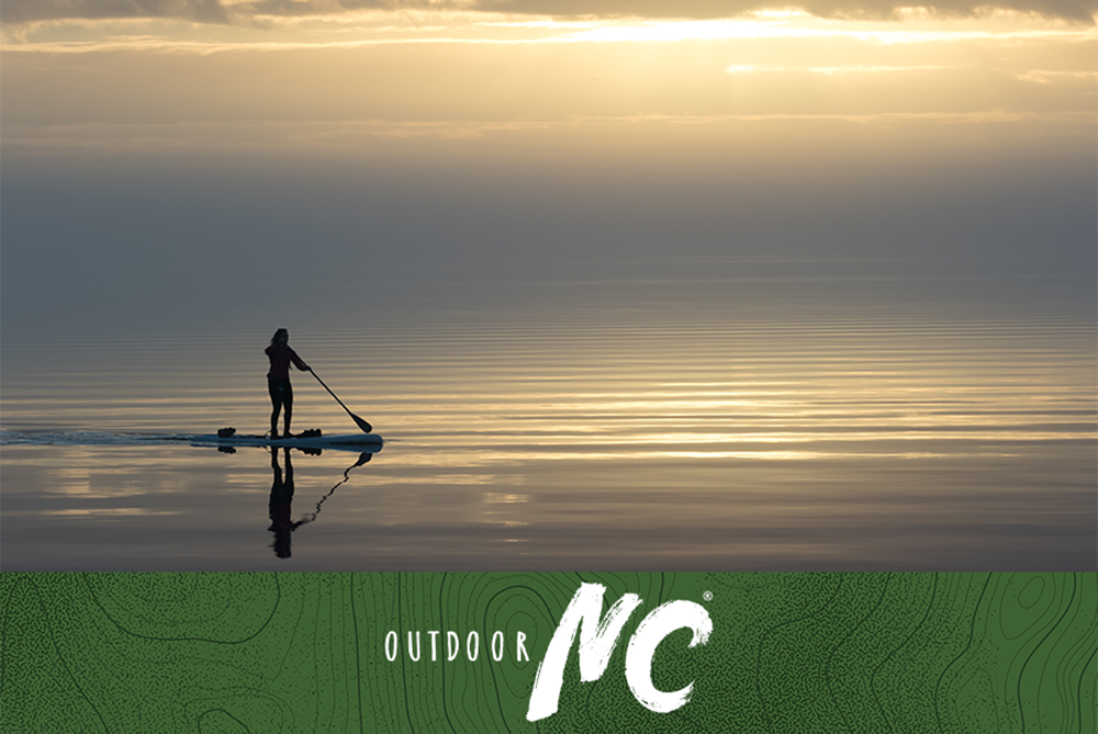 Silhouette of a standup paddle boarder out for a morning paddle on perfectly calm waters of the Neuse River along South Avenue in Oriental. The mouth of the Neuse River is the widest river in the United States and is a haven for sailing, fishing, boating and other water activities.