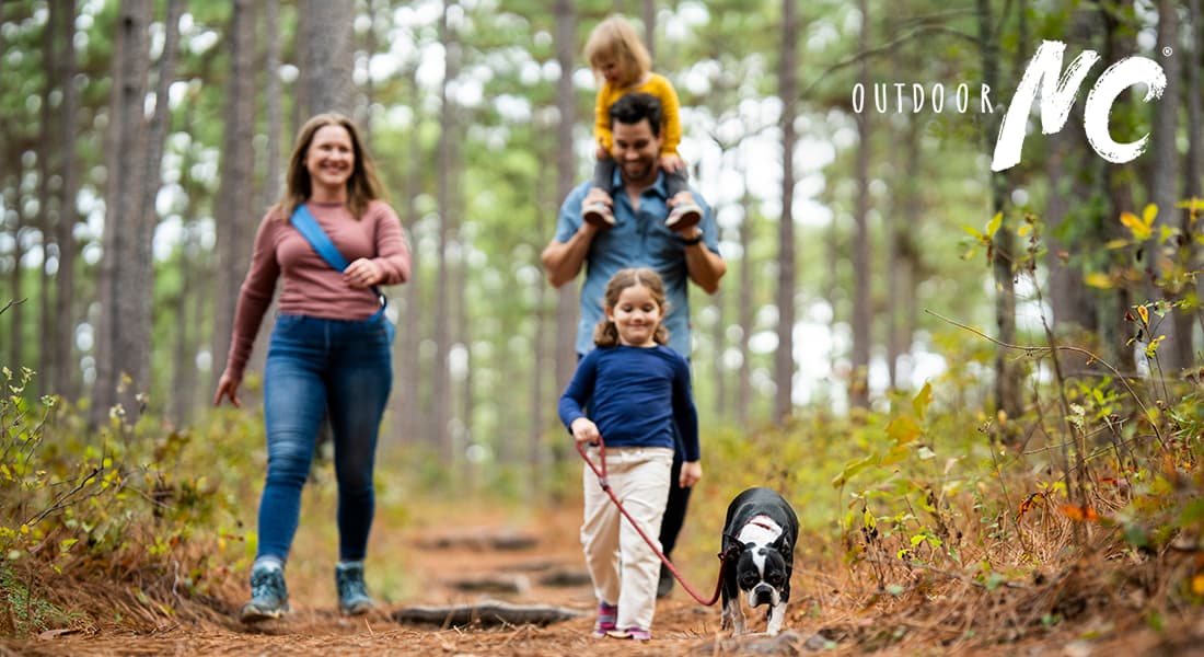 OUTDOOR NC - Family taking a walk with their dog on a wooded trail