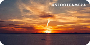 sunset over a lake with a small boat