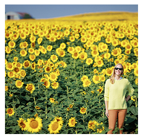 Woman standing and smiling in a sunflower field