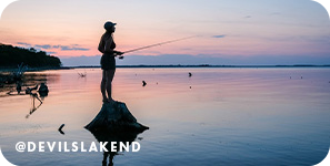 Silhouette of a person standing on a rock fishing in front of a sunset, with overlay text that reads @devilslakend