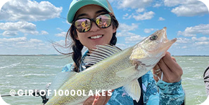 Girl holding a fish on a sunny day on a lake, with overlay text that reads @girlof10000lakes