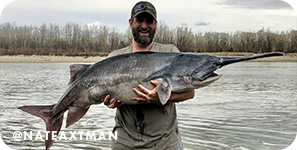 Man holding a very large fish in front of a lake, with overlay text that reads @nateaxtman
