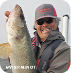 Man smiling and holding a large caught fish, with overlay text that reads @visitminot