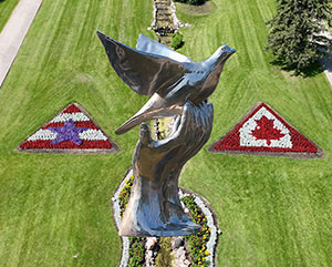 Metal statue of a bird with a garden below