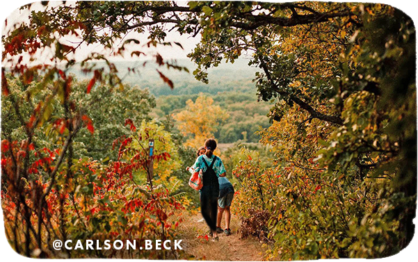 Kids walking on a trail surrounded by trees with red, green and yellow leaves, with overlay text that reads: @carlson.beck