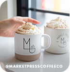 Hand reaching for two mugs of coffee beverages topped with whipped cream, with overlay text that reads: @marketpresscoffeeco