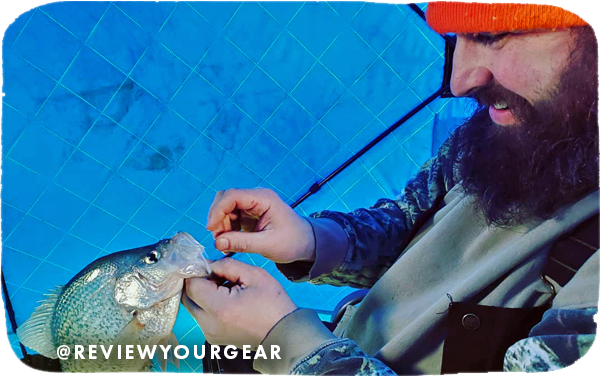 Close-up of a man unhooking a caught fish, with overlay text that reads: @reviewyourgear