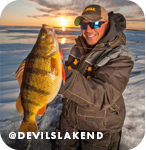 Man proudly holding up a caught fish in front of a frozen lake at sunset, with overlay text that reads: @devilslakend