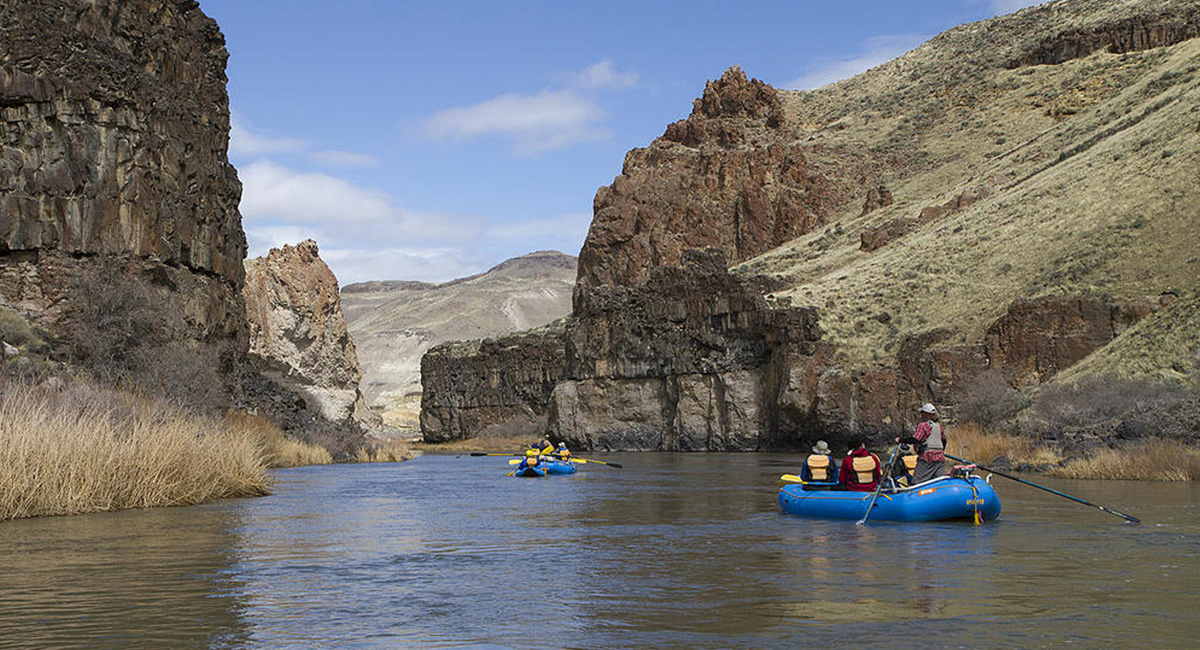 Two rafts float down a calm part of a river in Eastern Oregon's canyonlands.