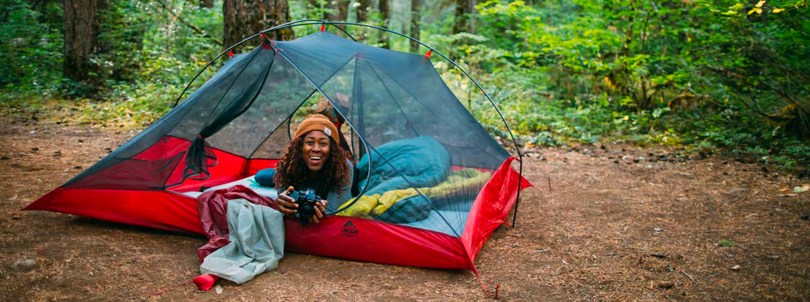 A person smiles from a red tent.
