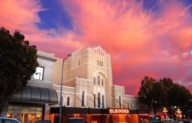 Historic Elsinore Theatre building under a vibrant pink and orange sunset sky.