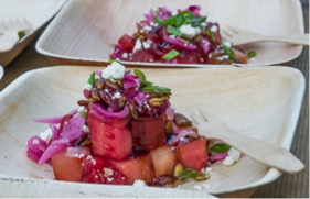 A vibrant watermelon salad served on a biodegradable plate.