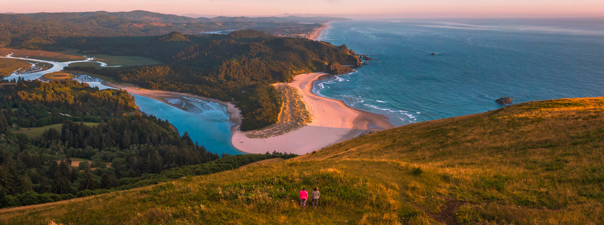 Aerial view of two people on a hill overlooking the ocean.