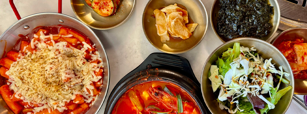 A flatlay of Korean dishes including ttekboki, kimchi, a prawn soup and seaweed.