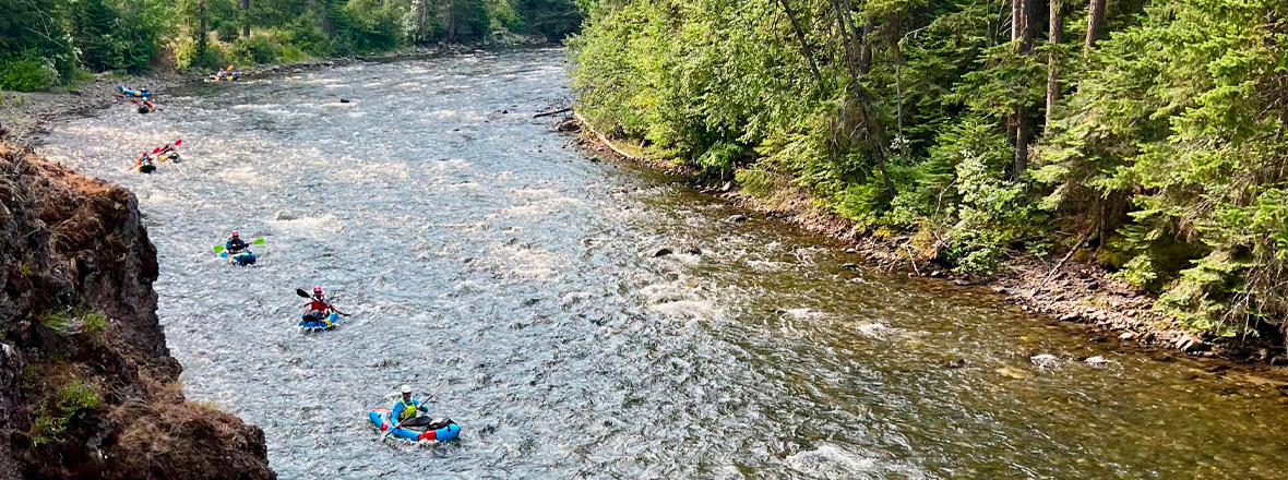 An aerial view of people kayaking down a clear river.